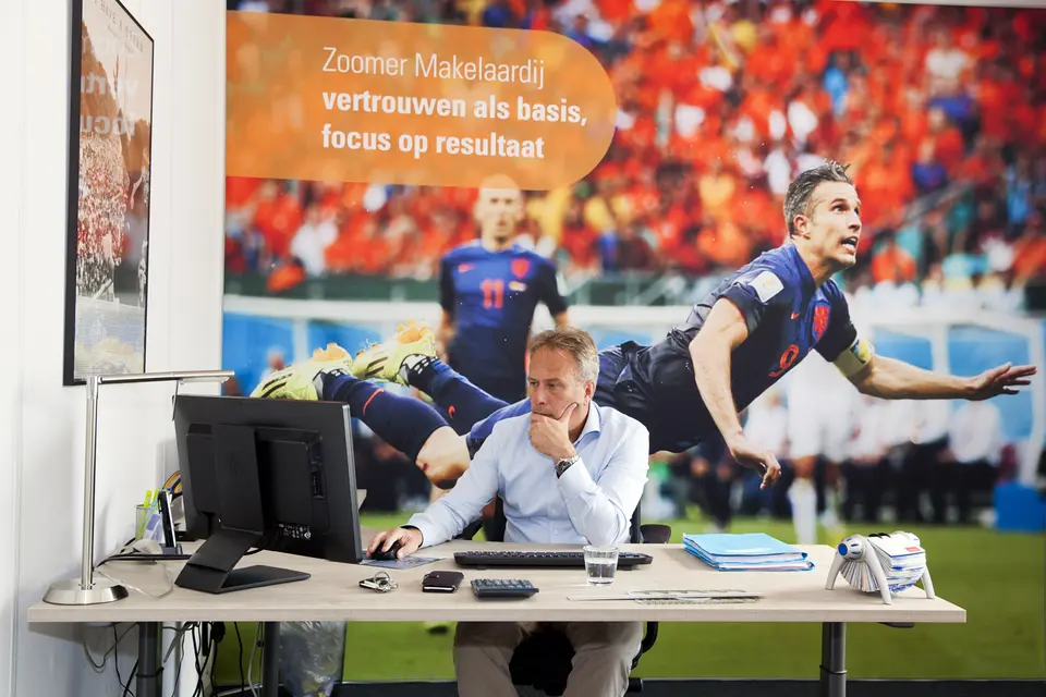 Makelaar bespreekt een woningbrochure met een klant op kantoor