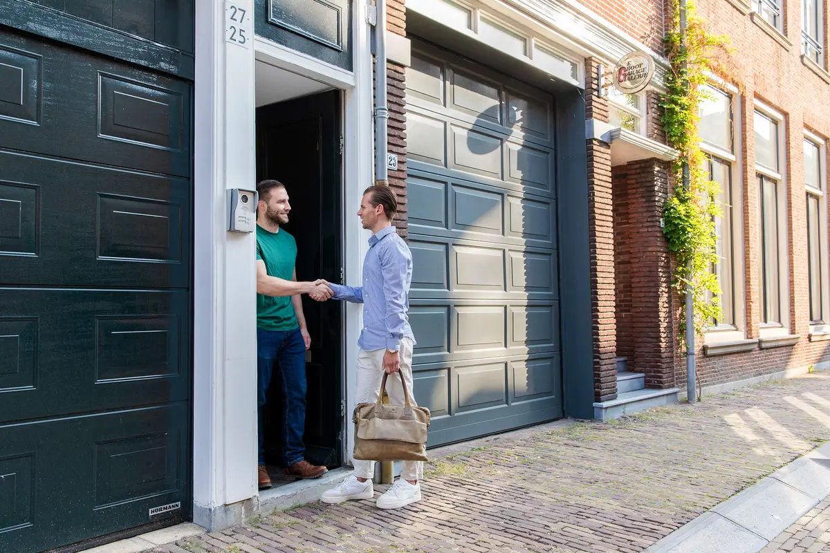 Makelaar schudt de hand van een bewoner bij de voordeur