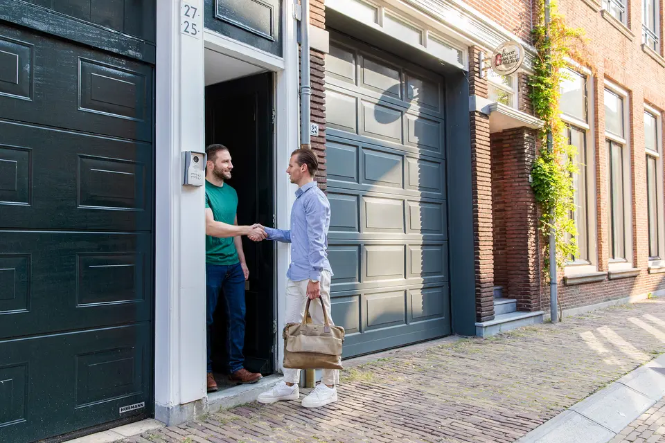 Makelaar schudt de hand van een bewoner bij de voordeur