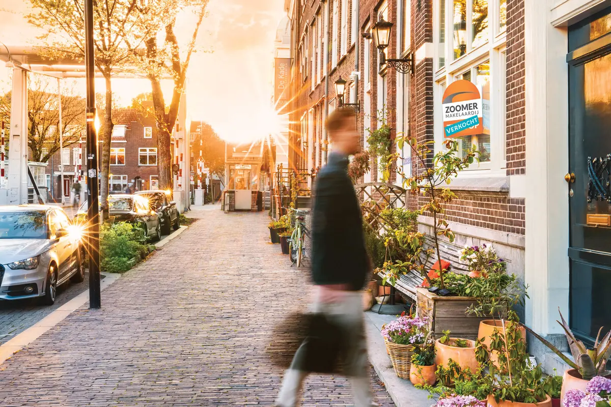 Straat in Dordrecht in warm najaarslicht met een verkocht-bord