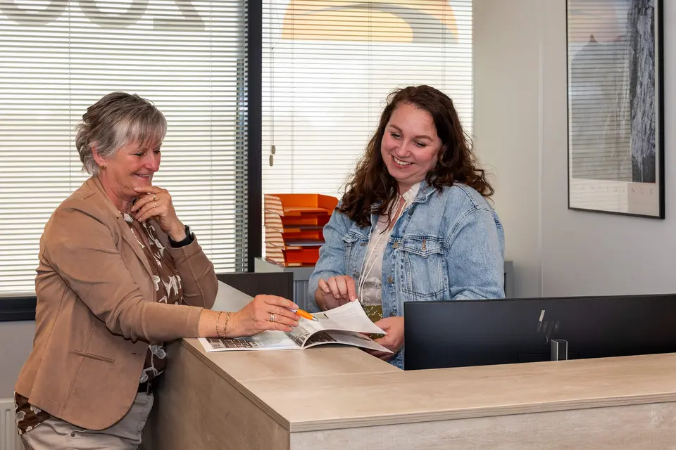 Makelaars bespreken een woningbrochure en mogelijke verbouwplannen